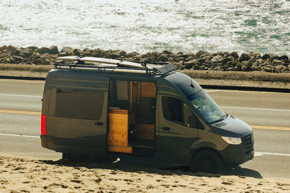 A person and their dog enjoying the view from an open campervan near a Phoenix lake