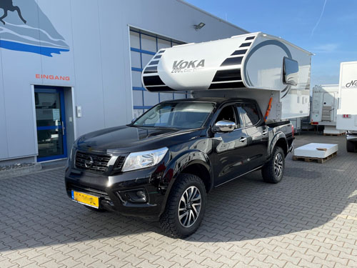 A modern truck camper parked in a desert landscape