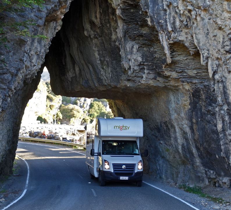 Mighty Campervan Driving Through a Rock Arch Tunnel in the American Southwest