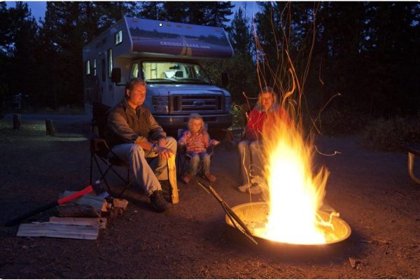 Family enjoying a campfire at night with a Class C motorhome