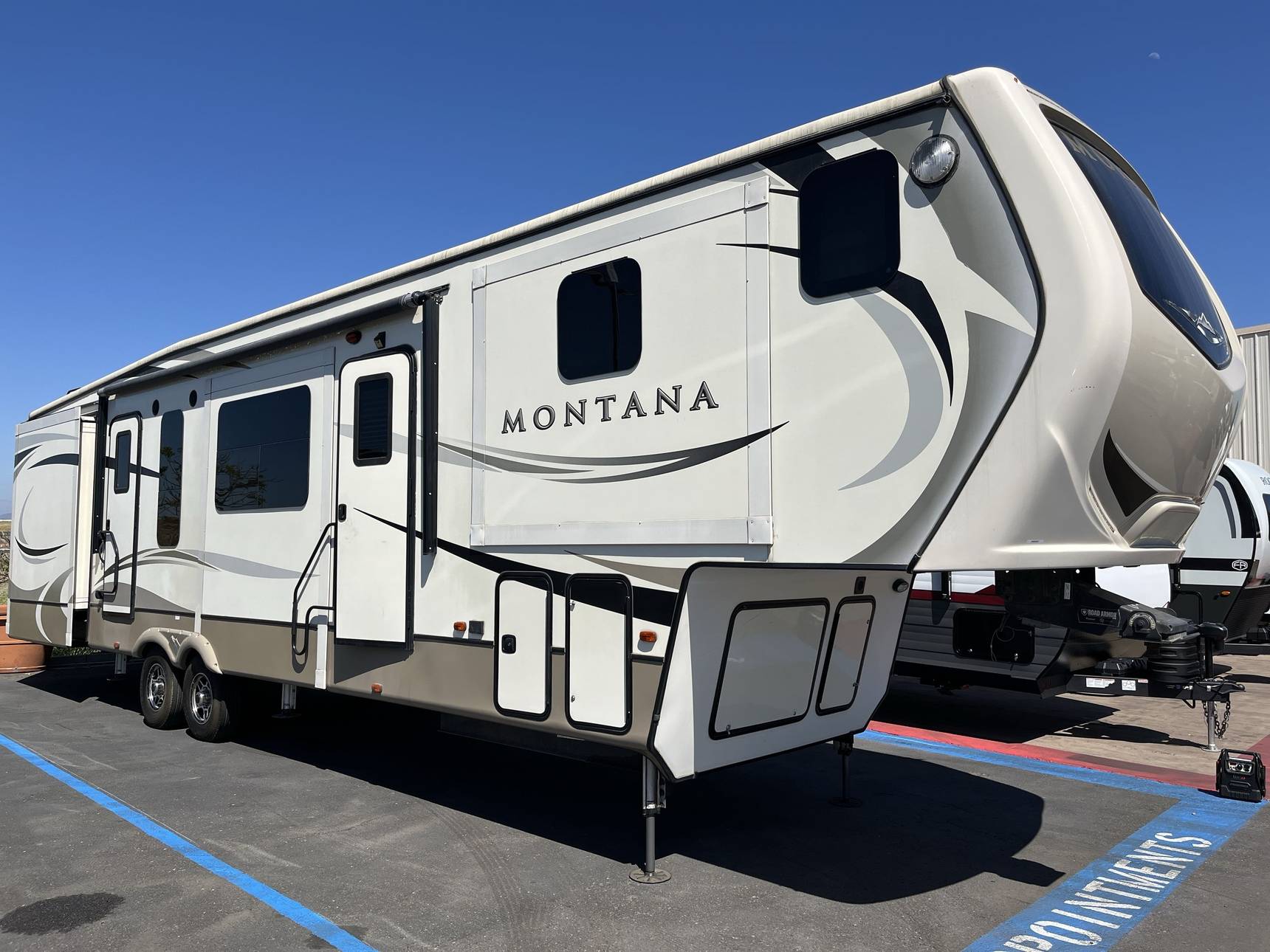 Different classes of RVs available for rent parked in a lot in San Diego