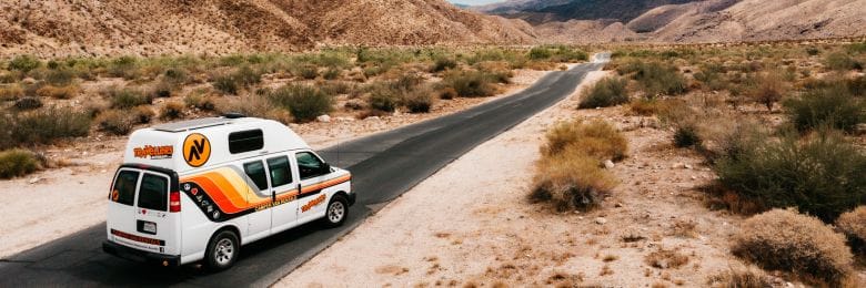 RV driving on a desert highway with Las Vegas in the background